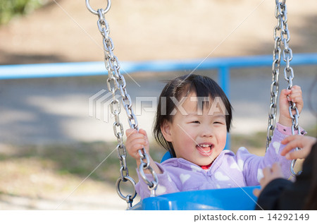 An infant playing a swing in a park 14292149
