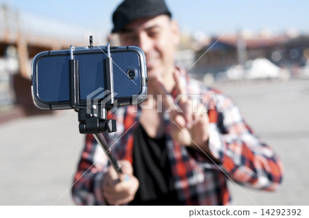 young man taking a selfie with a monopod 14292392