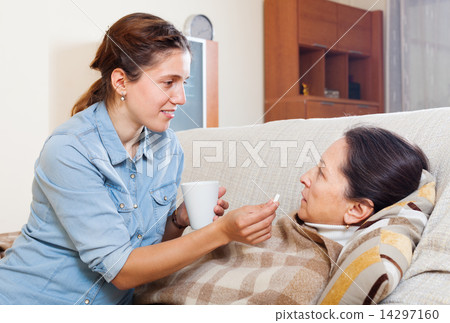 Adult daughter giving pills to mature woman Adult daughter giving pills to mature woman 14297160
