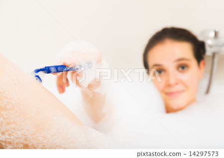 Young woman shaving legs 14297573