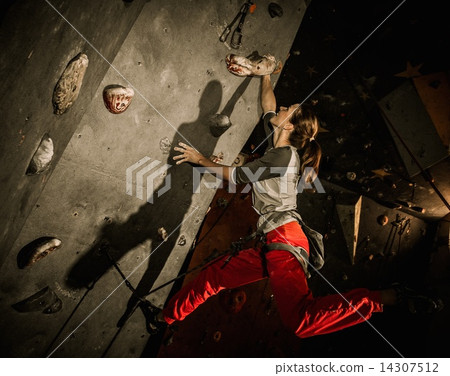 Young woman practicing rock-climbing on a rock wall indoors 14307512