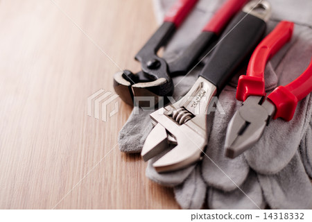 Adjustable wrench, pliers and nail puller on top of the protective gloves 14318332