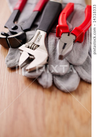 Adjustable wrench, pliers and nail puller on top of the protective gloves 14318333