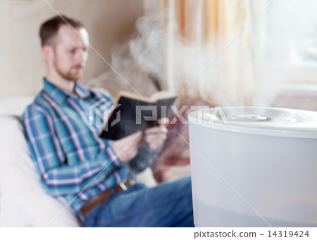 Man reading book on the background of humidifier Man reading book on the background of humidifier 14319424