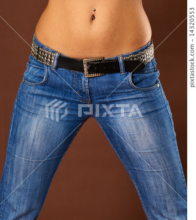 Young slim woman, close-up of tanned stomach, navel, hips, chest, wearing  jeans, lying on towel Stock Photo - Alamy