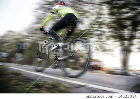 Low angle view of cyclist riding mountain bike with speed effect Low angle view of cyclist riding mountain bike with speed effect 14323014
