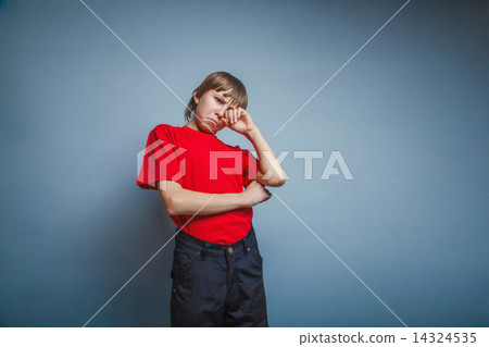 Boy, teenager, twelve years red in T-shirt, hand wipes tears, sa 14324535
