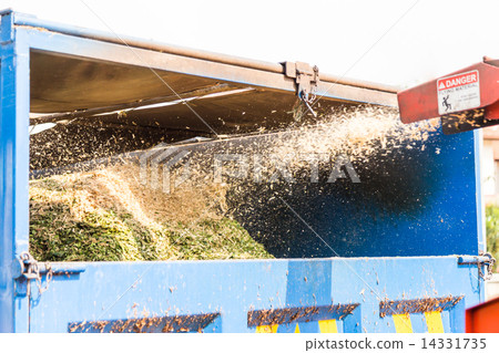 Wood chipper machine releasing the shredded woods into a truck 14331735