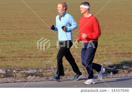 Two people running in the cold winter weather. Two people running in the cold winter weather. 14337048