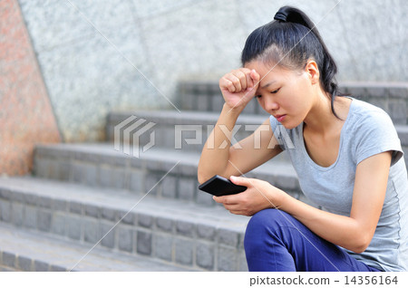 lonely young asian woman hold smart phone sit on stairs 14356164