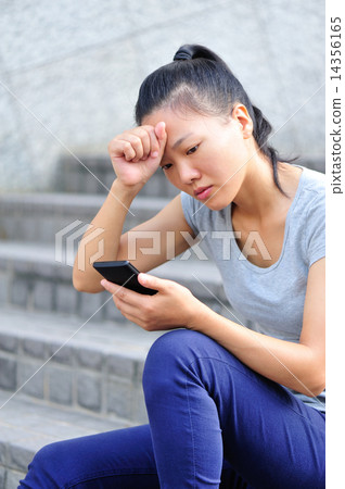 lonely young asian woman hold smart phone sit on stairs 14356165