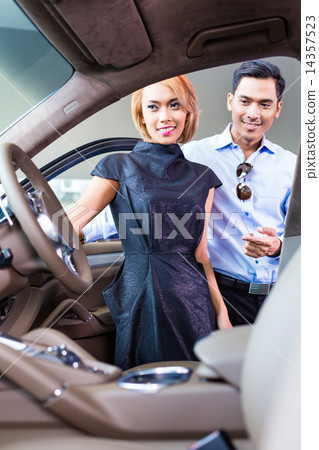 Asian couple choosing luxury car in dealership 14357523