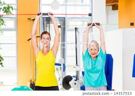 Young and old woman in gym training strength with rod Young and old woman in gym training strength with rod 14357553