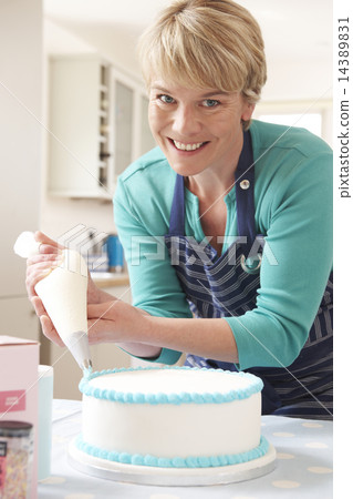 Woman Icing Birthday Cake In Kitchen At Home Woman Icing Birthday Cake In Kitchen At Home 14389831