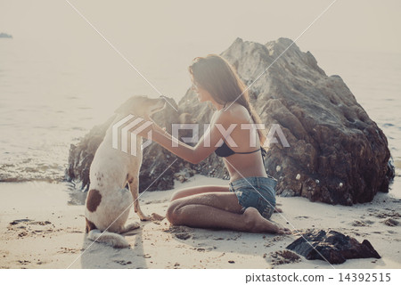 Portrait of beautiful happy young woman sitting playing her pet dog sunset at the beach on sea shore 14392515