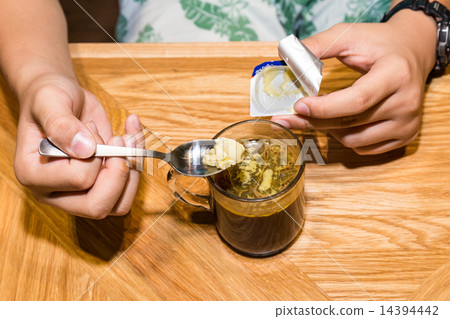 Person adding butter to black coffee 14394442