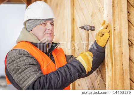 Carpenter drives a nail in board  14403129