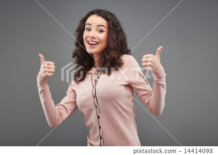 Young woman smiling and showing thumbs up Young woman smiling and showing thumbs up 14414098