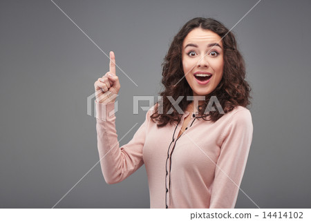 Young woman looking at camera and pointing up 14414102