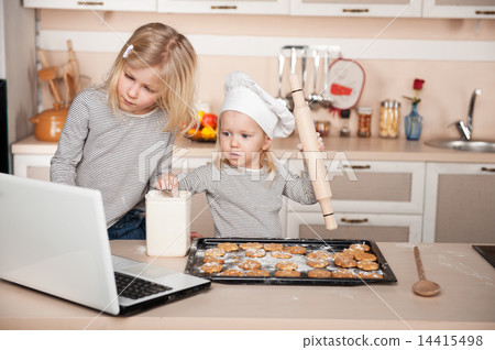 Little sisters preparing cookies and searching for recipes online 14415498