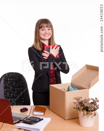 Girl puts a photo frame on desktop in office 14419053