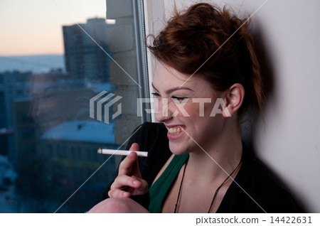 Beautiful young woman smoking on evening window. Beautiful young woman smoking on evening window. 14422631