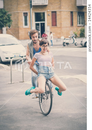 couple of friends young man and woman riding bike 14424354
