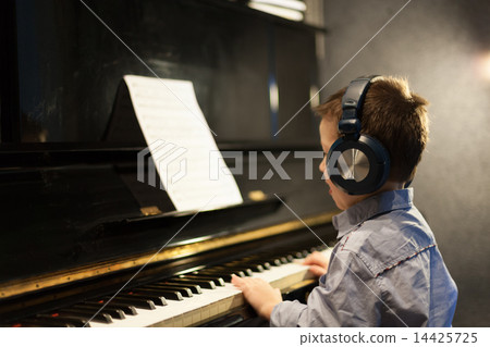 Boy listening to music and learning piano Boy listening to music and learning piano 14425725