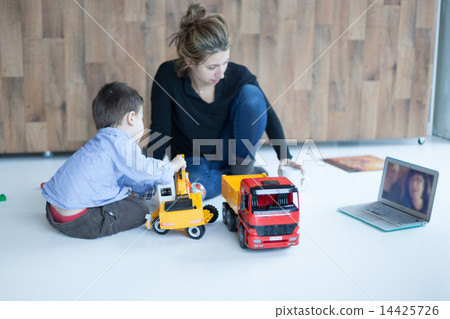 Boy playing toys with his mother video calling to her parents Boy playing toys with his mother video calling to her parents 14425726