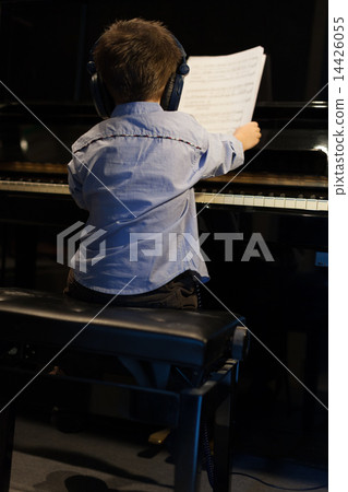 Rear view of a little boy learning piano Rear view of a little boy learning piano 14426055