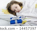 Little girl sleeping in bed with gift 14457397