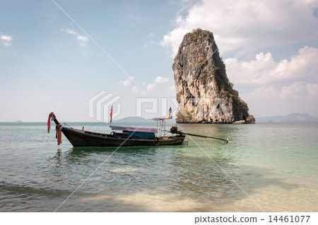 Wooden long-tail boat floating near a beach with rocky island in the background 14461077