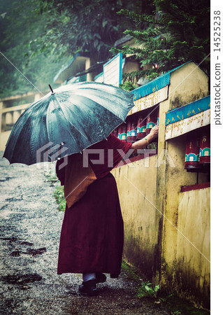 Buddhist monk with umbrella spinning prayer wheels Buddhist monk with umbrella spinning prayer wheels 14525238