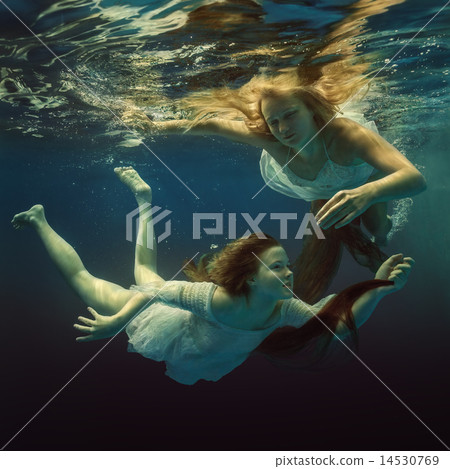 Woman and girl in beautiful dresses swim underwate Woman and girl in beautiful dresses swim underwate 14530769