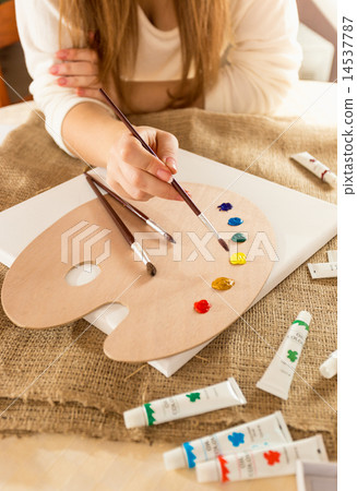 young female artist sitting at table and drawing on canvas young female artist sitting at table and drawing on canvas 14537787