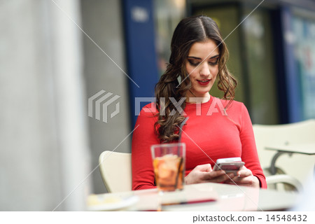 Young woman looking at her smartphone sitting in a cafe 14548432