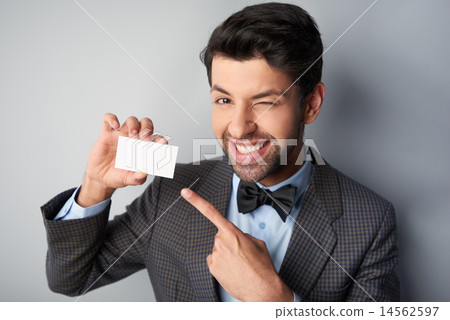 smiling man pointing at blank visiting card and winking 14562597