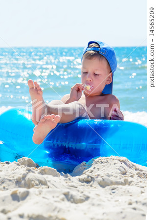 kid with ice cream on beach sitting in water tube kid with ice cream on beach sitting in water tube 14565209