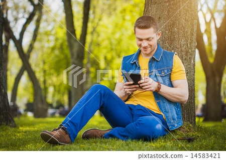 Handsome young man with tablet in the park 14583421