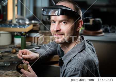 Jeweler silver soldering in his workshop. Jeweler silver soldering in his workshop. 14589255