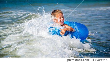 happy boy enjoying swimming in sea with rubber ring happy boy enjoying swimming in sea with rubber ring 14589943