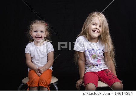 Portrait of two young girls sitting on chairs 14614594