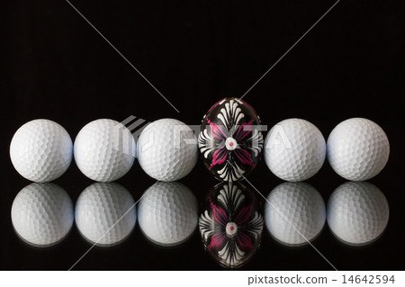 Golf balls and egg on a black glass table 14642594