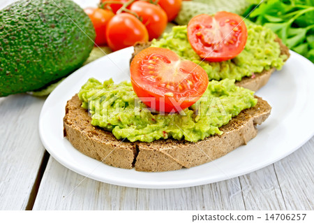 Sandwich with guacamole avocado and tomato on light board 14706257