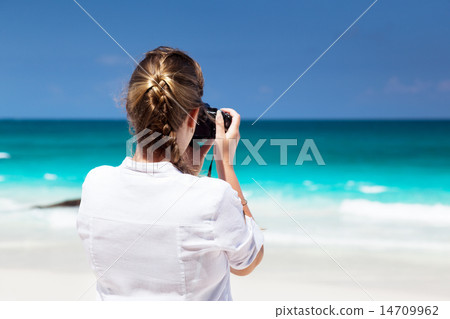 woman on tropical beach taking photo with mirrorless camera 14709962