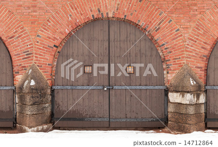 Old locked wooden gate in red brick fortress wal 14712864