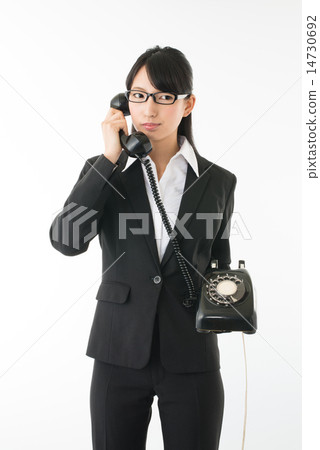 A woman in a suit in talking with an analog line's black phone A woman in a suit in talking with an analog line's black phone 14730692