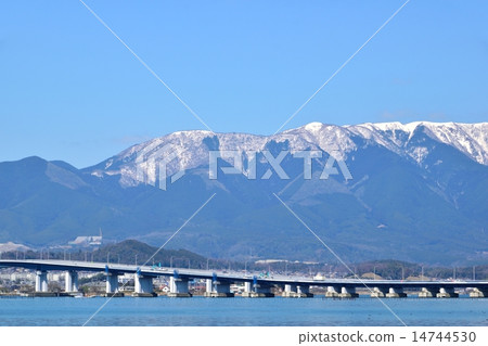 The Lake Biwa Ohashi bridge passing through Biwa lake in early spring and Higarashi Mountain of snow as the background 14744530
