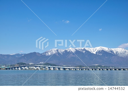 The Lake Biwa Ohashi bridge passing through Biwa lake in early spring and Higarashi Mountain of snow as the background The Lake Biwa Ohashi bridge passing through Biwa lake in early spring and Higarashi Mountain of snow as the background 14744532