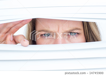 Woman peering through roller blind 14745900